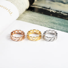 Cassie braided rose gold ring displayed alongside gold and silver braided rings on a white surface