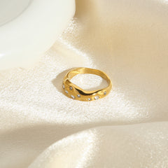 Elegant gold snake shape ring adorned with small gemstones on a silky fabric background