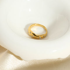 Gold snake shape ring with embedded clear gemstones displayed on a white dish