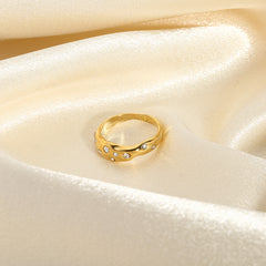 Gold snake shape ring with embedded stones on a shiny satin fabric background
