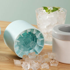 Portable silicone ice maker bucket in light blue with clear ice cubes spilling on wooden surface