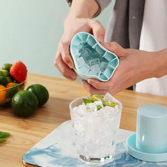 Portable silicone ice maker bucket releasing ice cubes into a glass on a wooden table