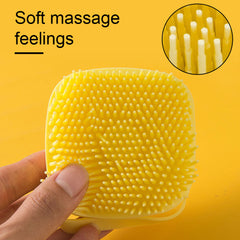 Yellow soft silicone dog brush with soft massage bristles held in hand against yellow background